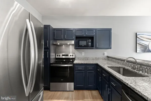 a kitchen with granite countertop a refrigerator stove and sink