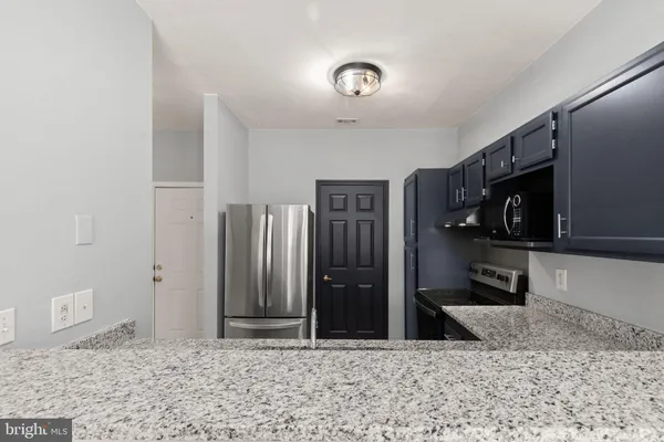 a living room with stainless steel appliances kitchen island granite countertop a refrigerator and a sink