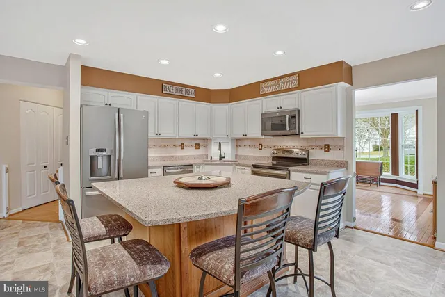 a kitchen with stainless steel appliances granite countertop a stove a sink a refrigerator a microwave oven with a dining table and chairs