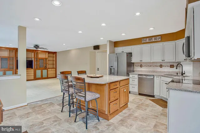 a kitchen with stainless steel appliances granite countertop a table chairs sink and cabinets