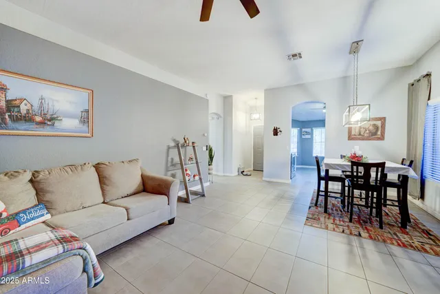 a living room with furniture and a dining table with bookshelf