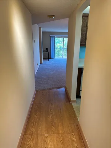 a view of a hallway with wooden floor and a bathroom