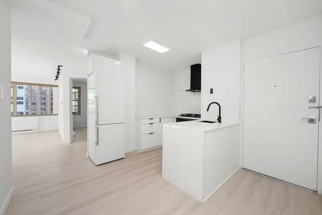 a view of kitchen with refrigerator and white cabinets