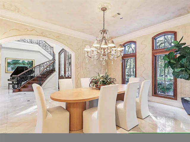 a view of a dining room with furniture a chandelier and large windows