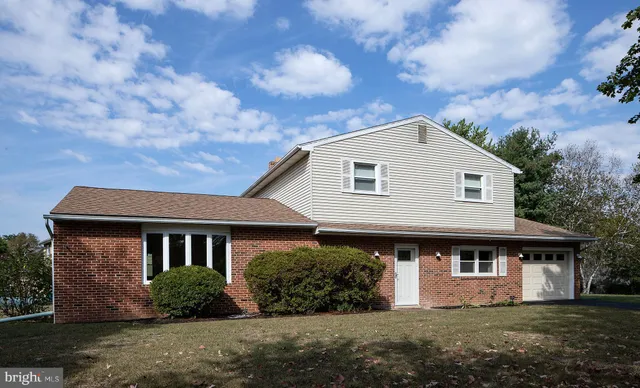 a view of a house with a yard and large tree