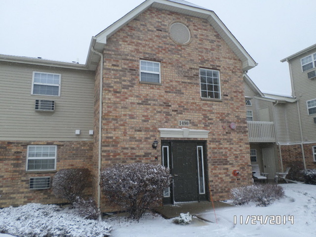 1490 Spring Brook Court, Unit 1G Round Lake Beach, IL 60073 - Photo 1 of 12 a front view of a house with plants