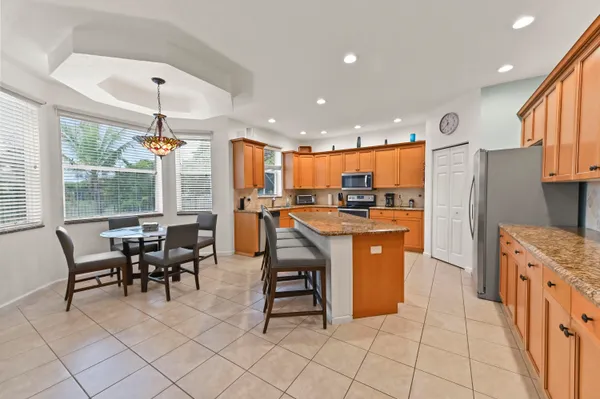 a kitchen with stainless steel appliances granite countertop a table chairs and a refrigerator