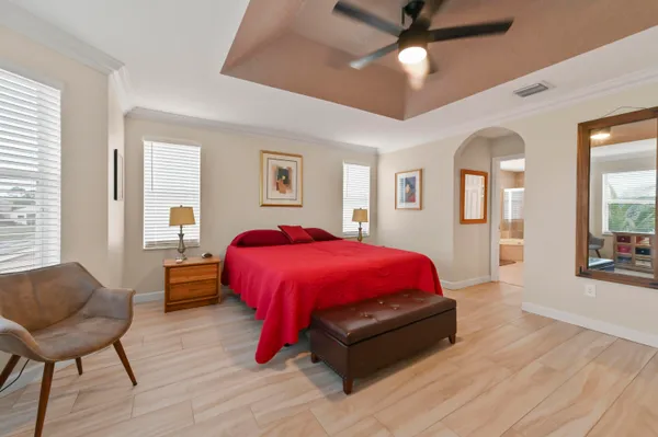 a spacious bedroom with a bed a dresser and wooden floor