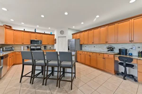 a kitchen with stainless steel appliances granite countertop a stove a sink a microwave a island with a dining table and chair