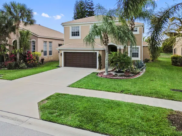 a front view of a house with a yard and palm tree