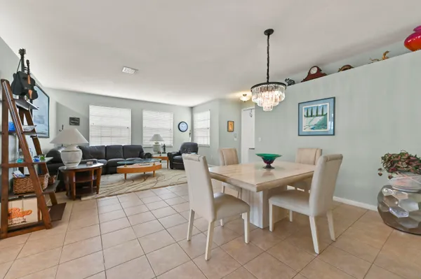 a view of a dining room and livingroom with furniture wooden floor a rug a painting and a chandelier