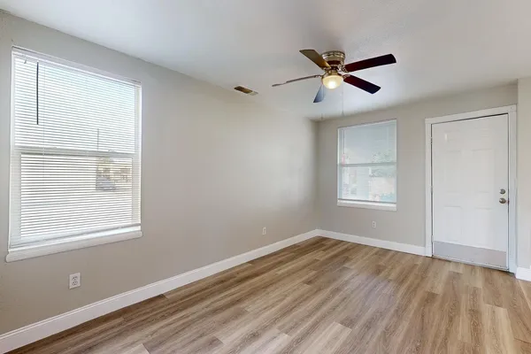 a view of empty room with wooden floor and fan