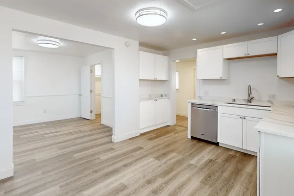 a kitchen with a sink cabinets stainless steel appliances and wooden floor