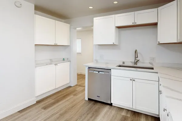 a kitchen with white cabinets stainless steel appliances sink and wooden floor