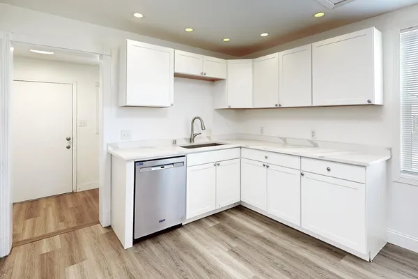 a kitchen with white cabinets white appliances sink and center island