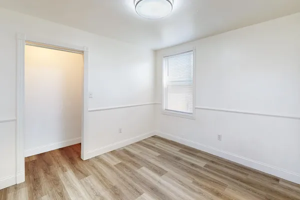 an empty room with wooden floor and windows