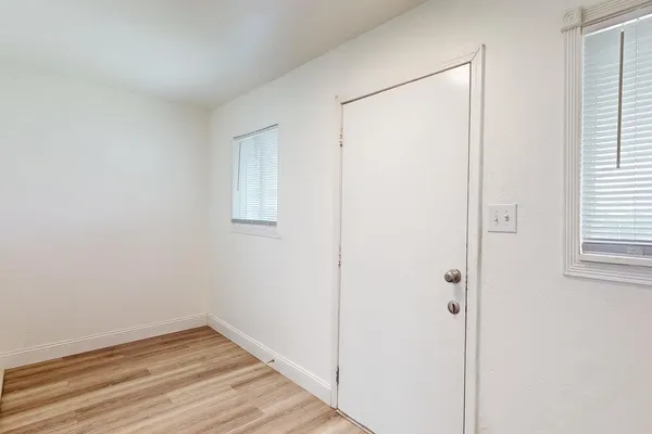 a view of an empty room with wooden floor and a window