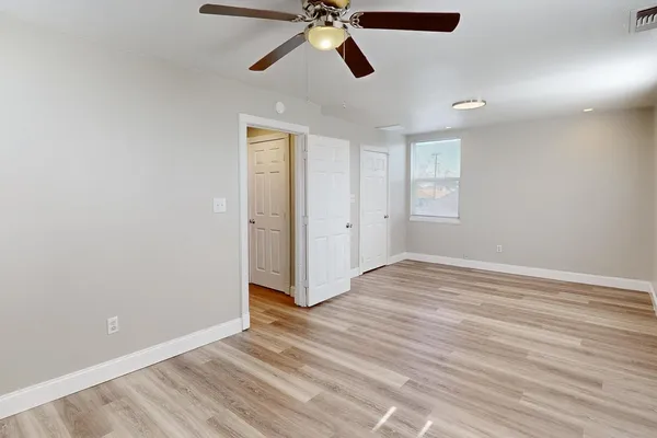an empty room with wooden floor and ceiling fan