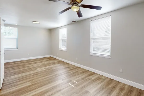 a view of an empty room with wooden floor and a window