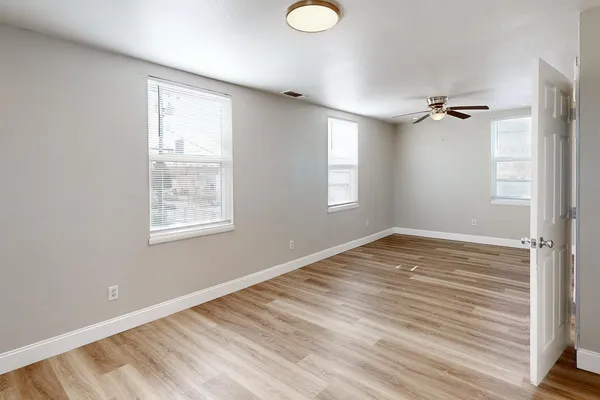 a view of empty room with wooden floor and fan