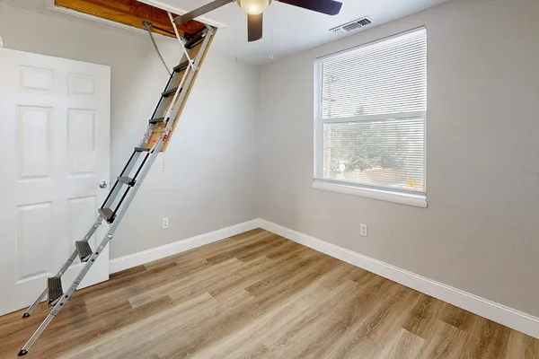 a view of an empty room with wooden floor and stairs