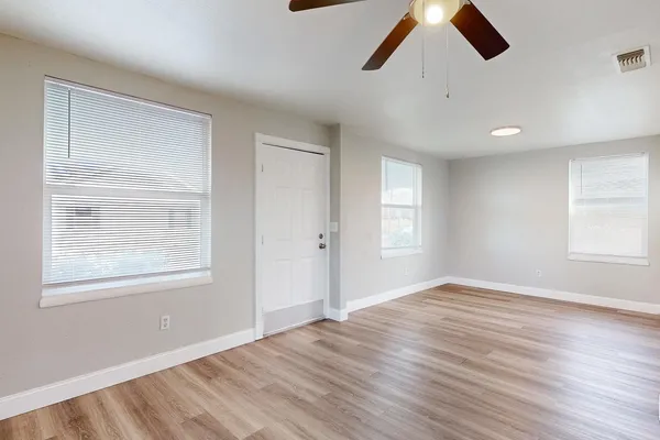 a view of an empty room with wooden floor and window