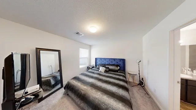 a bedroom with a bed and a flat tv screen on a dresser