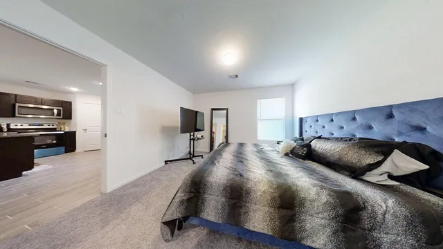 a bedroom with a large bed and a view of kitchen