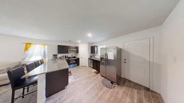 a living room with stainless steel appliances furniture and a kitchen view