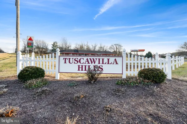 a sign board in front of a road with a house