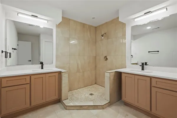 a bathroom with a double vanity sink mirror and shower