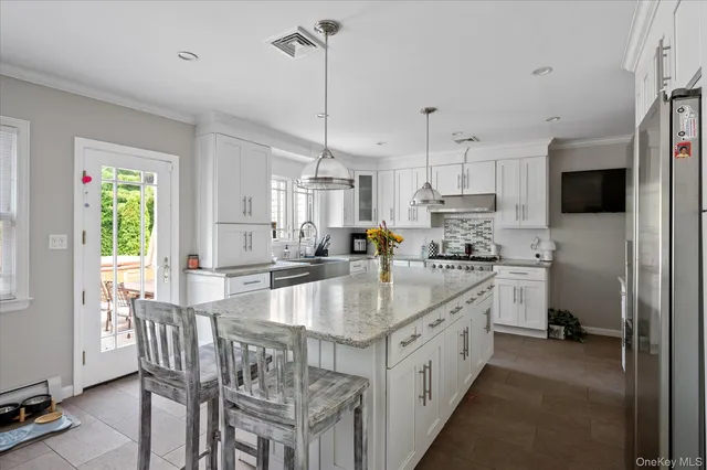 a large kitchen with kitchen island granite countertop lots of counter space a sink appliances and cabinets