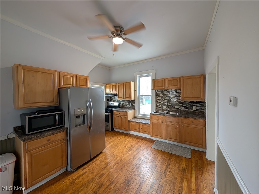 10143 Pleasant Road Pleasant City, OH 43772 - Photo 10 of 32 Kitchen featuring appliances with stainless steel finishes, tasteful backsplash, light wood-style flooring, a ceiling fan, and ornamental molding