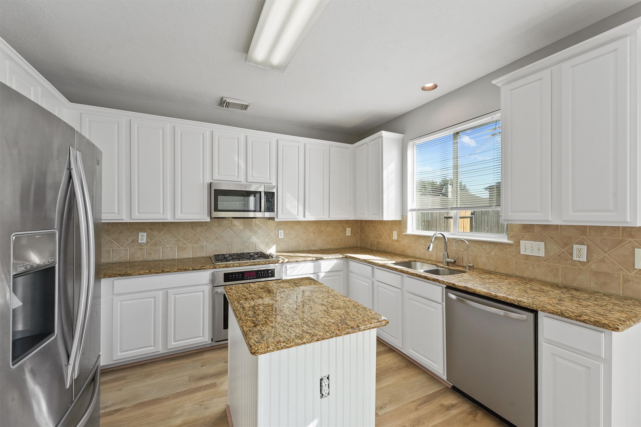 9107 Huckinston Court Spring, TX 77379 - Photo 10 of 32 a kitchen with granite countertop a sink stove and refrigerator