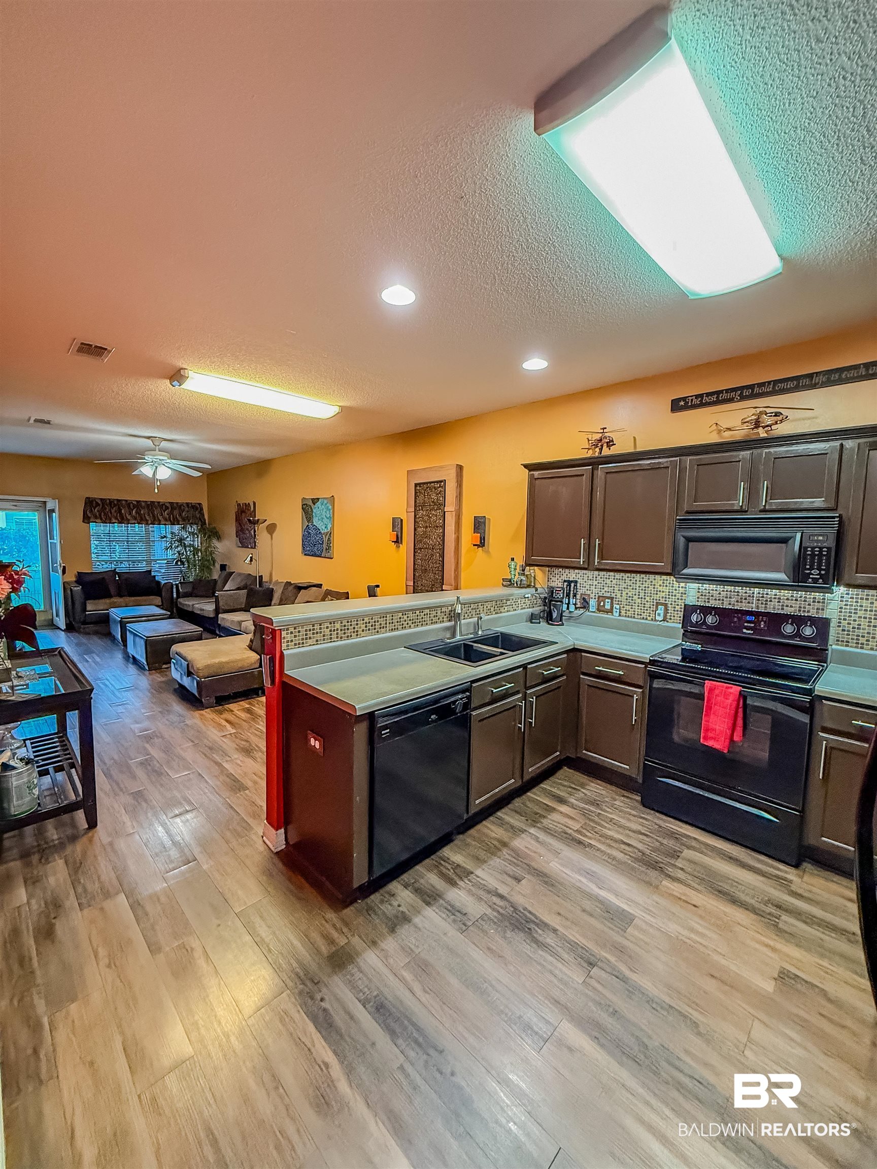 2651 South Juniper Street Foley, AL 36535 - Photo 20 of 20 Kitchen with a peninsula, black appliances, dark brown cabinets, open floor plan, and a textured ceiling