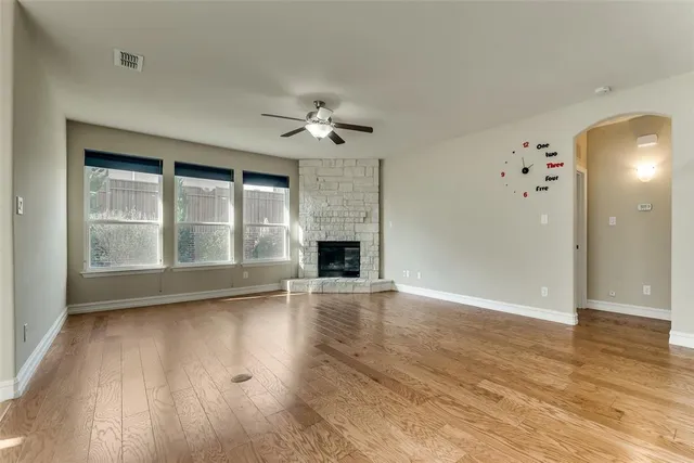 an empty room with wooden floor fireplace and windows