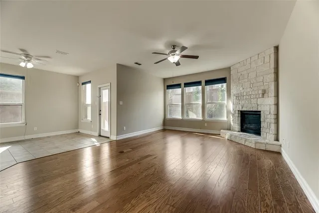 a view of an empty room with a fireplace and wooden floor
