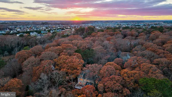 a view of a white house with a large trees with wooden fence