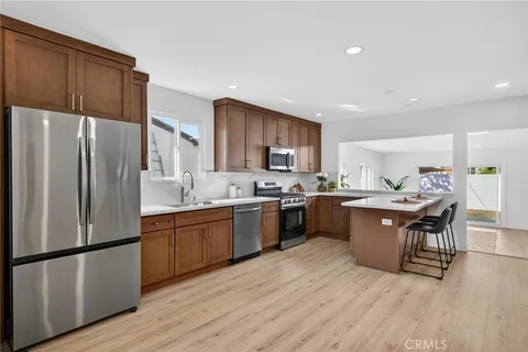 a kitchen with stainless steel appliances granite countertop a refrigerator a sink dishwasher a stove with wooden floors and cabinets