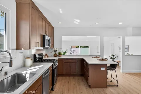 a kitchen with a sink a stove cabinets and wooden floor