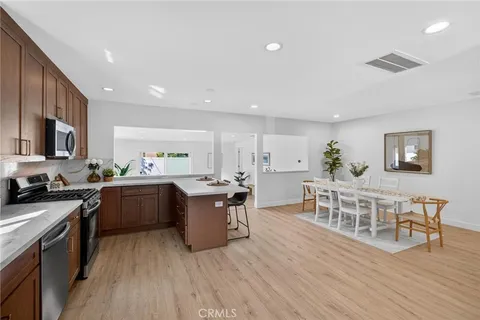 a kitchen with stainless steel appliances a dining table chairs stove refrigerator and cabinets