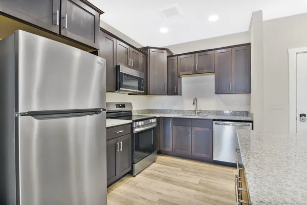 a kitchen with stainless steel appliances granite countertop a refrigerator a stove and a sink