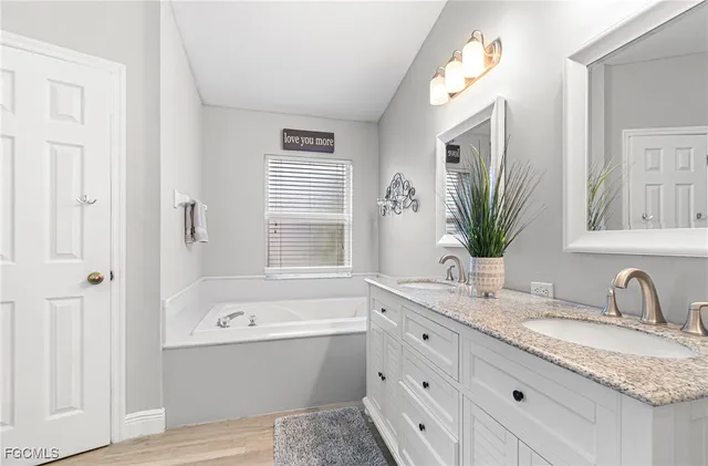 a bathroom with a granite countertop sink mirror and a bathtub