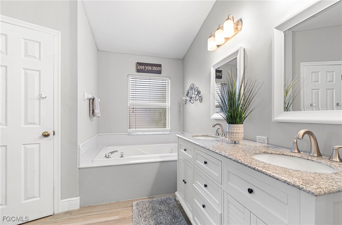4656 Varsity Circle Lehigh Acres, FL 33971 - Photo 21 of 49 a bathroom with a granite countertop sink mirror and a bathtub