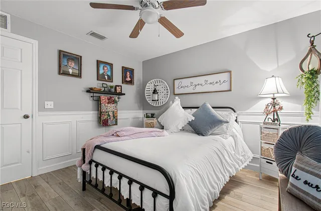 a bedroom with a bed a painting on the wall and dresser