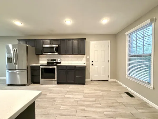 a kitchen with stainless steel appliances kitchen island granite countertop a refrigerator and a stove top oven