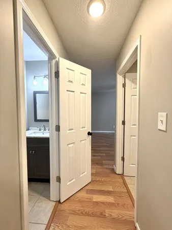 a view of a hallway with wooden floor and cabinets