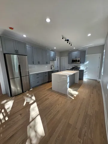a large white kitchen with wooden floors and stainless steel appliances