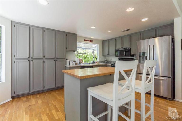 560 Fairfield Road Simi Valley, CA 93065 - Photo 10 of 32 a kitchen with stainless steel appliances granite countertop a refrigerator a stove a sink dishwasher and white cabinets with wooden floor