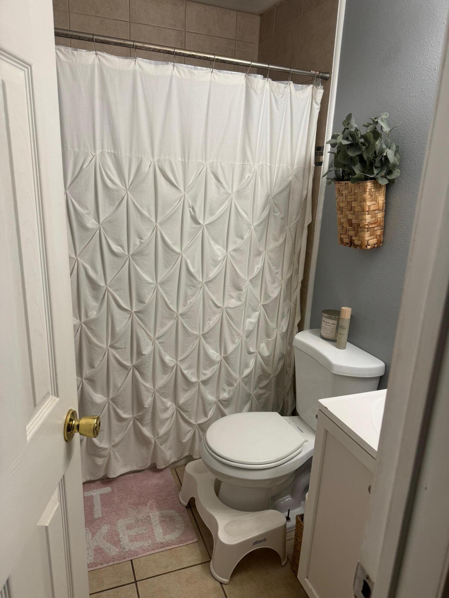 2312 15th Street Lubbock, TX 79401 - Photo 19 of 20 a white toilet sitting next to a shower curtain